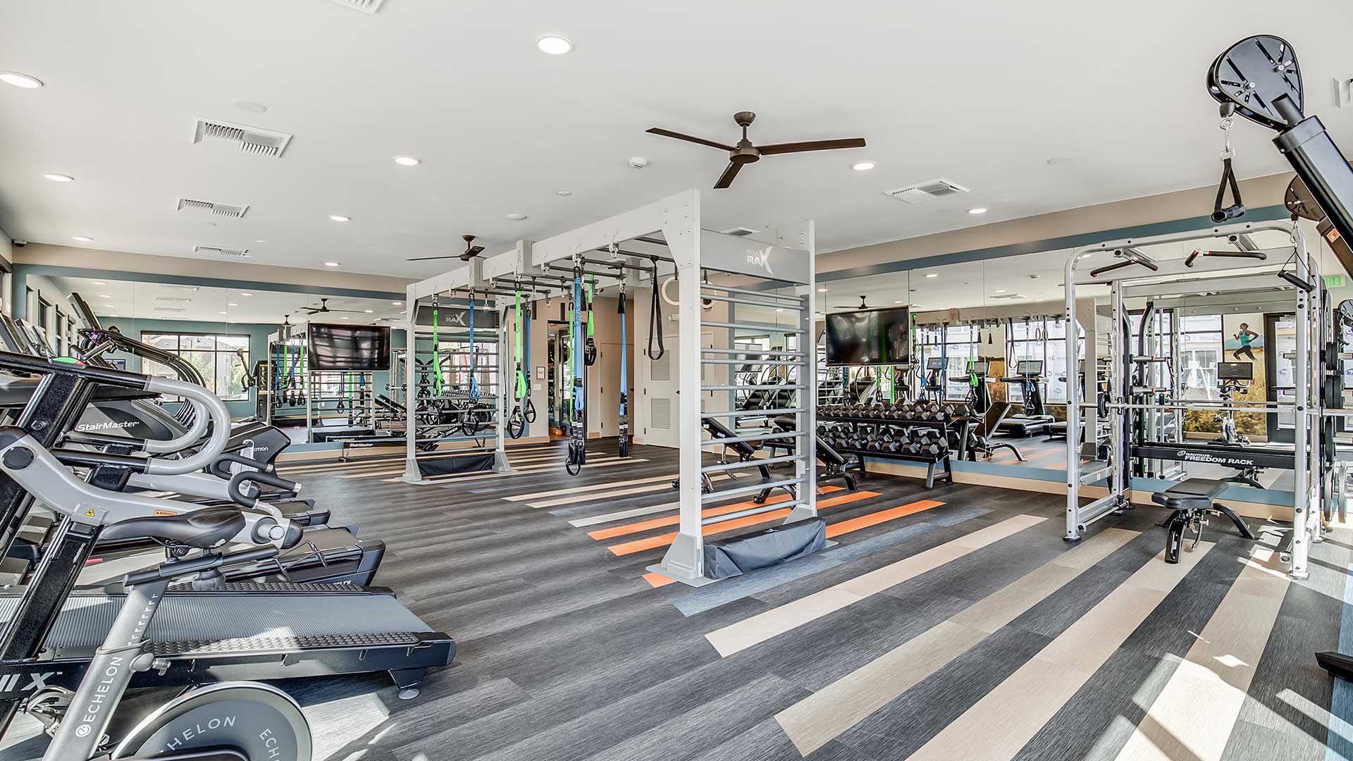 Modern fitness center at The Wright featuring cardio equipment, strength training machines, free weights, and functional workout areas with natural light.