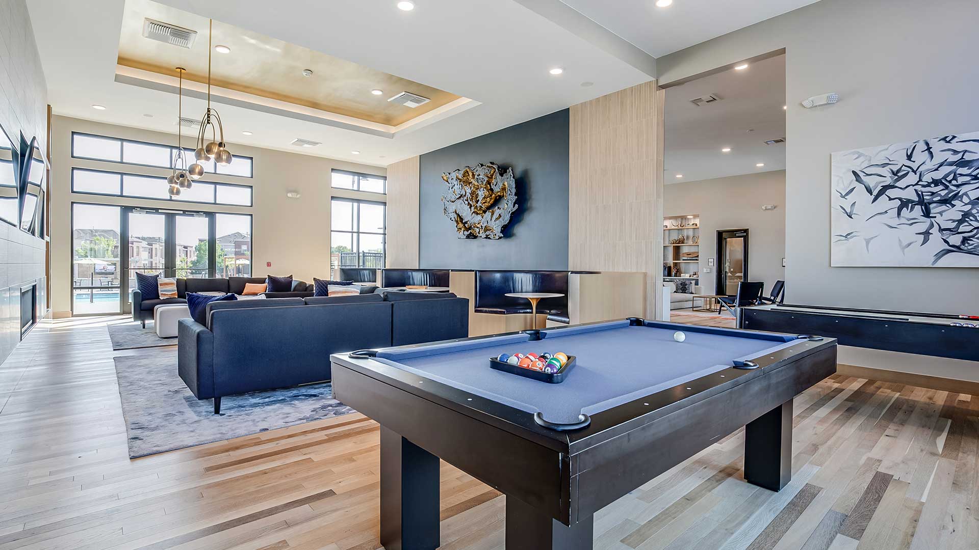 Modern resident clubhouse at The Wright with pool tables, lounge seating, designer lighting, and open social gathering spaces.