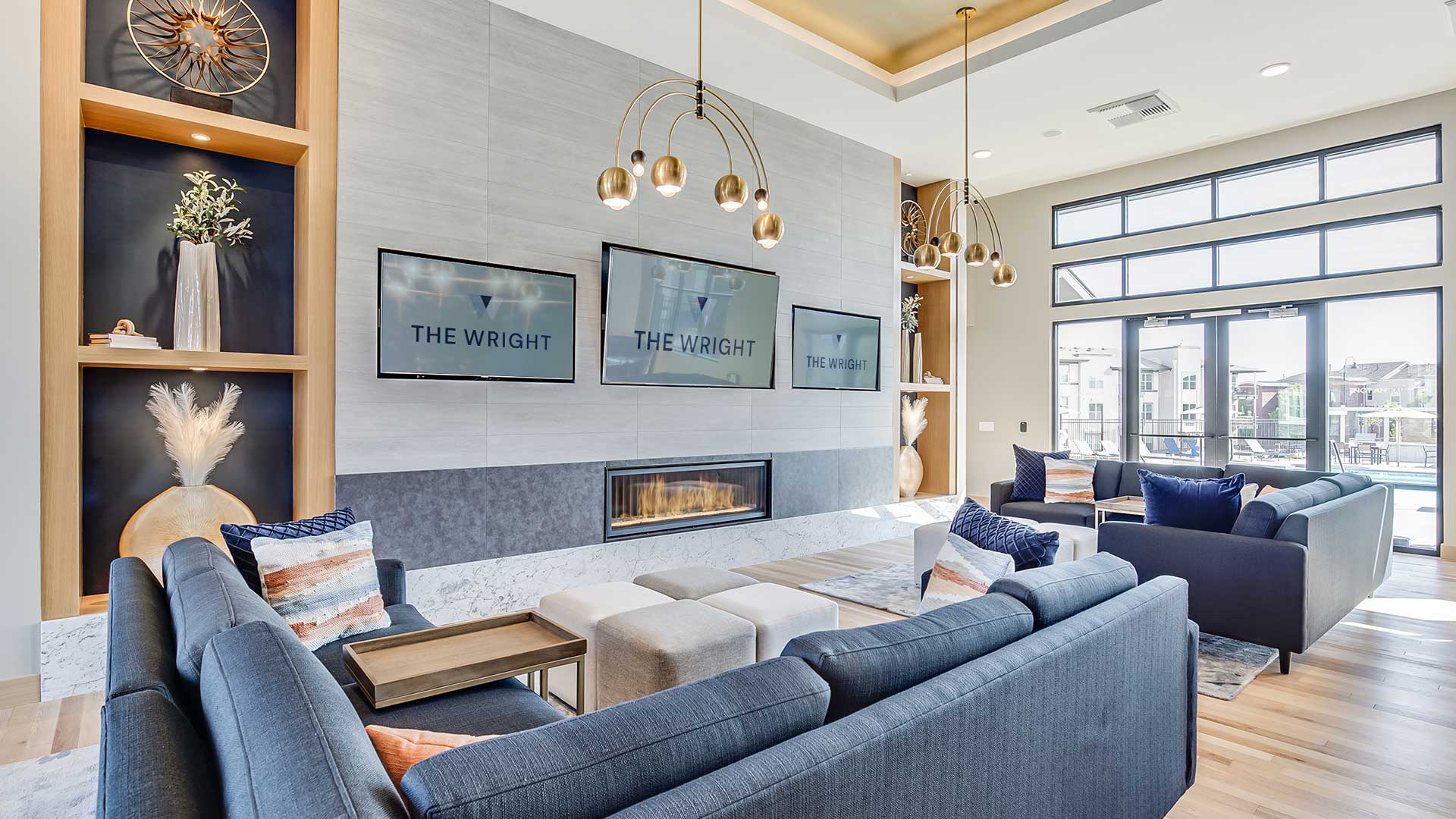 Upscale resident lounge at The Wright with modern seating areas, fireplace, designer lighting, and large windows overlooking the community amenities.