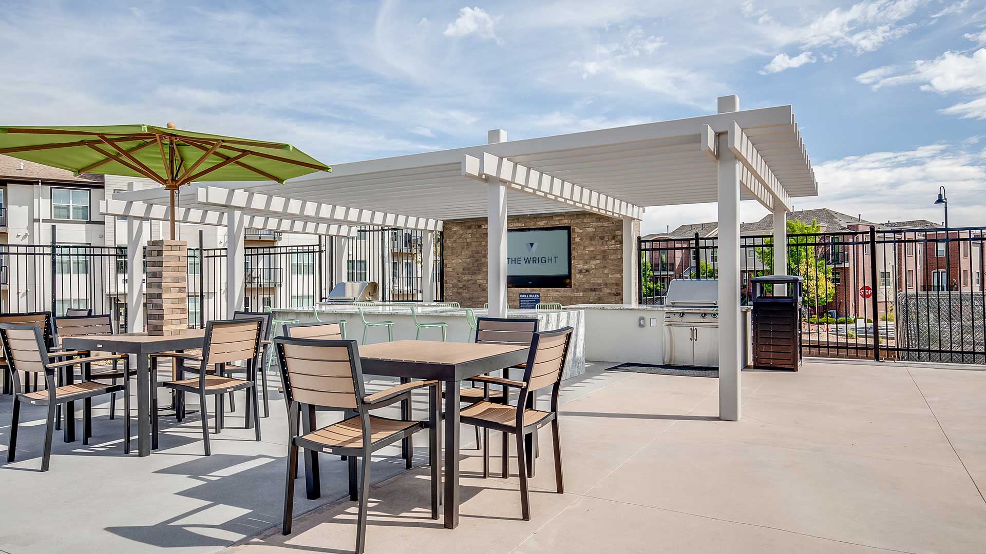 Outdoor entertainment area at The Wright featuring grilling stations, shaded seating, dining tables, and modern community gathering spaces.