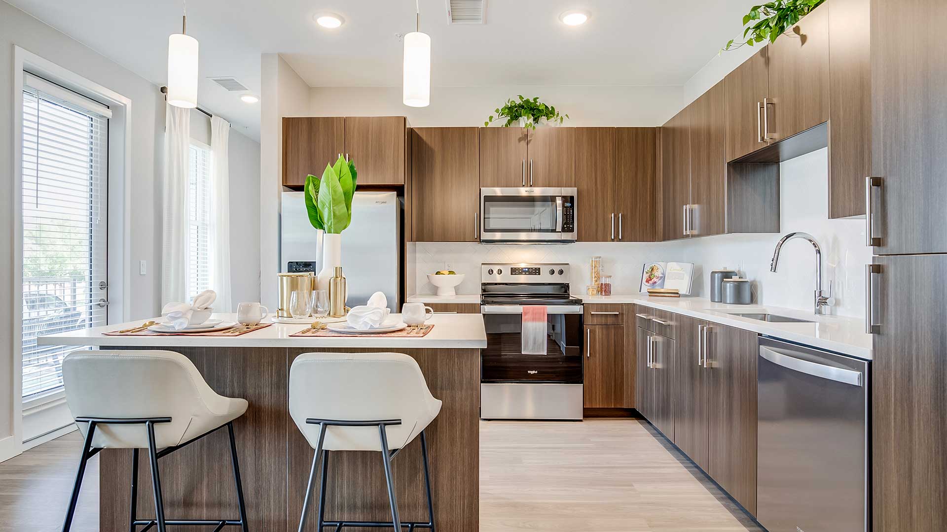Modern apartment kitchen at The Wright featuring quartz countertops, stainless-steel appliances, custom cabinetry, and an open-concept layout with island seating.
