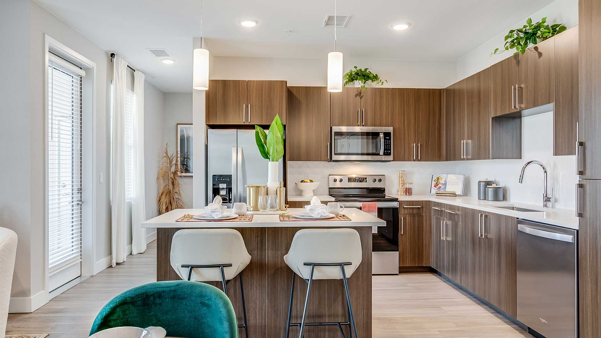 Modern apartment kitchen at The Wright with quartz countertops, stainless-steel appliances, wood-style cabinetry, and a large island with seating.